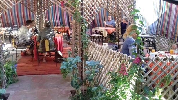 An outdoor dining area with tables and chairs, surrounded by a bamboo lattice structure. - Hostel take your time 4235 (Zagora)