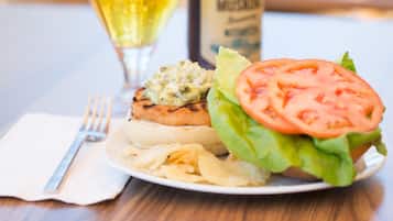 A meal with a burger, a glass of beer, and a bottle of beer on a table.