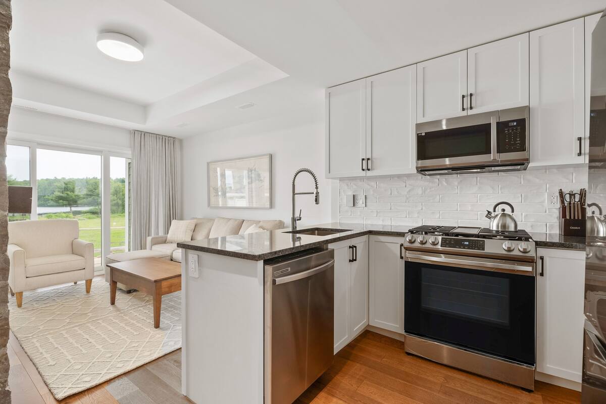 A modern kitchen with white cabinets, stainless steel appliances, and a built-in oven.