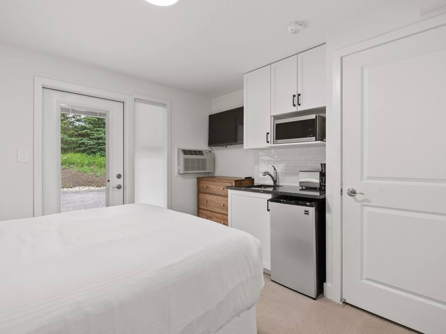 Una camera compatta con un letto, angolo cottura e un accesso a un'area esterna.