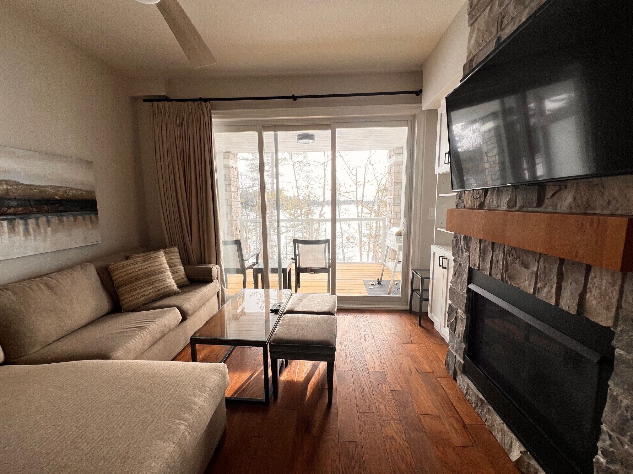 A living room with a sofa, coffee table, and fireplace. There is a sliding glass door leading to an outdoor deck.