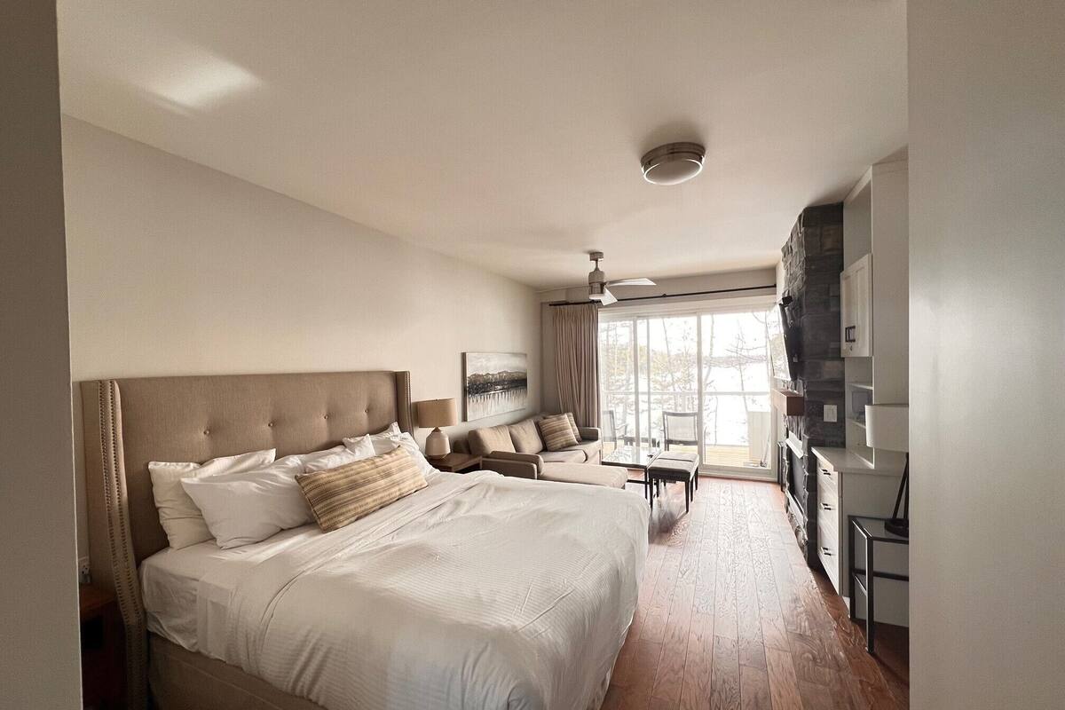 A spacious bedroom with a large bed, a desk, and a TV.