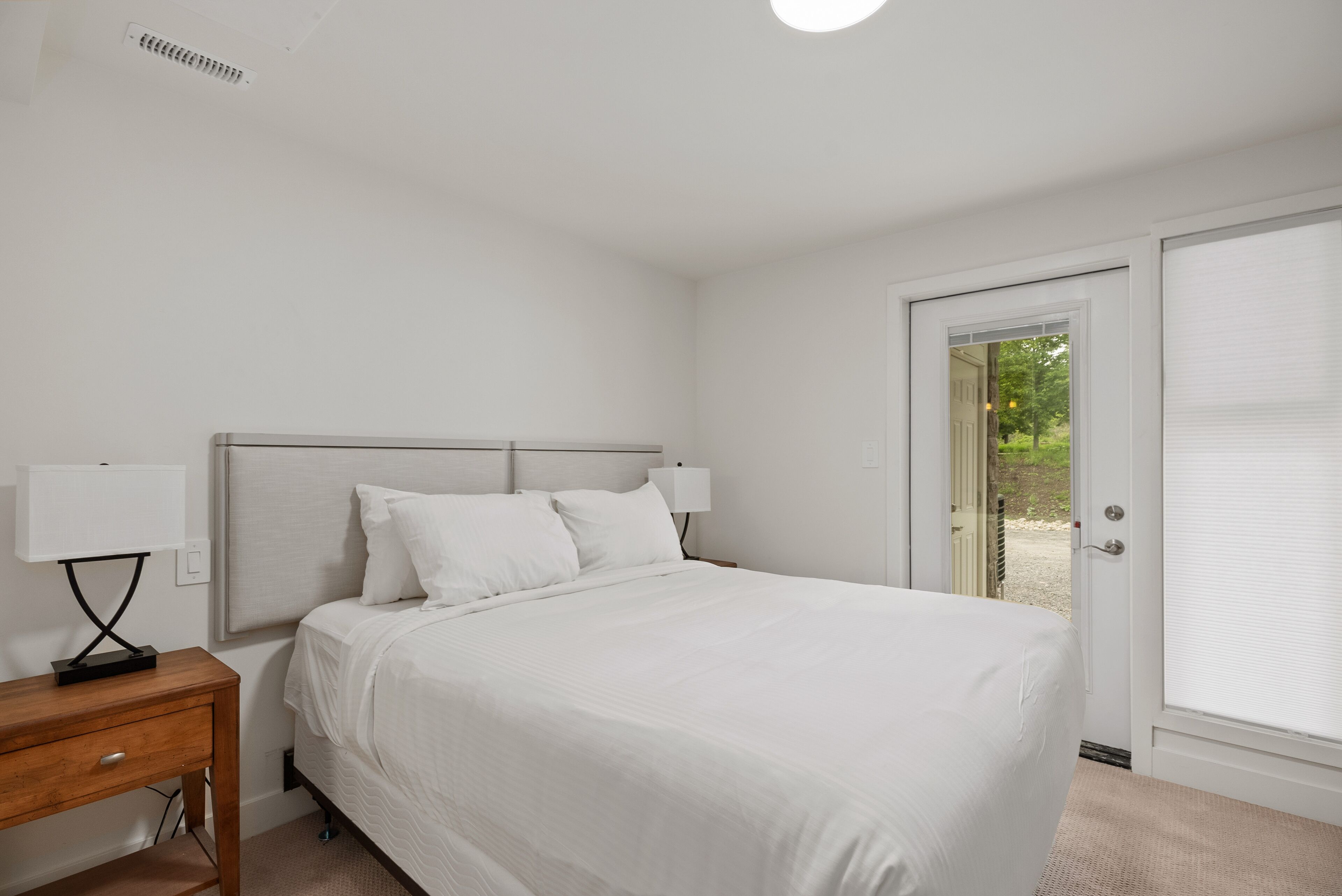 Ein Schlafzimmer mit einem Bett, Nachttischen und einer Tür, die auf einen Balkon führt.