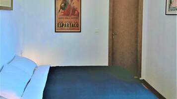 A bedroom with a bed, a door, and a poster on the wall.