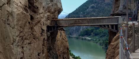 A bridge over a river canyon with rocky cliffs on either side.