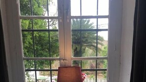 Una mesa de desayuno con diversos alimentos y bebidas, una lámpara y vistas al exterior con vegetación.