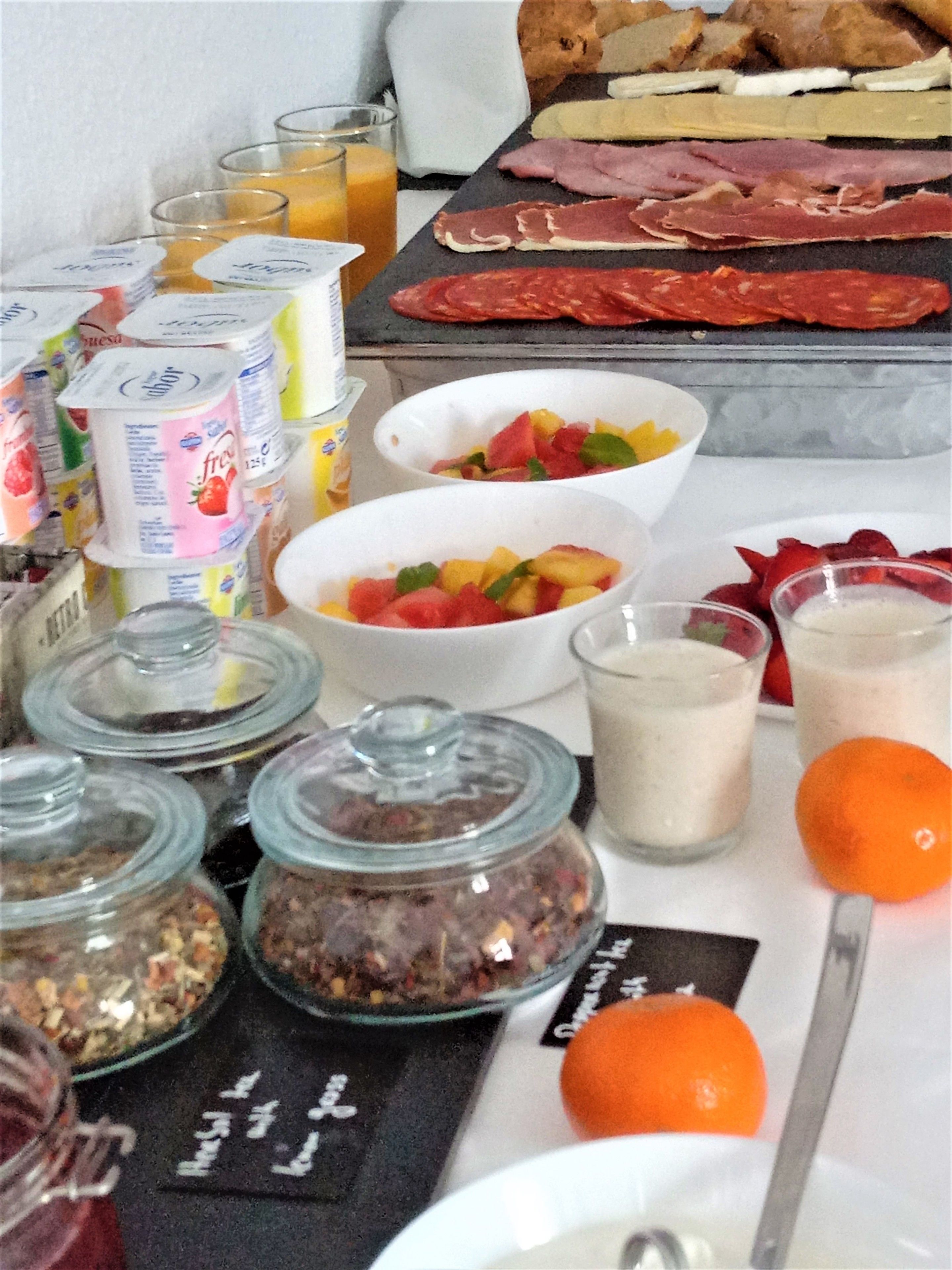 A breakfast buffet with various food items, including meats, fruits, and beverages.
