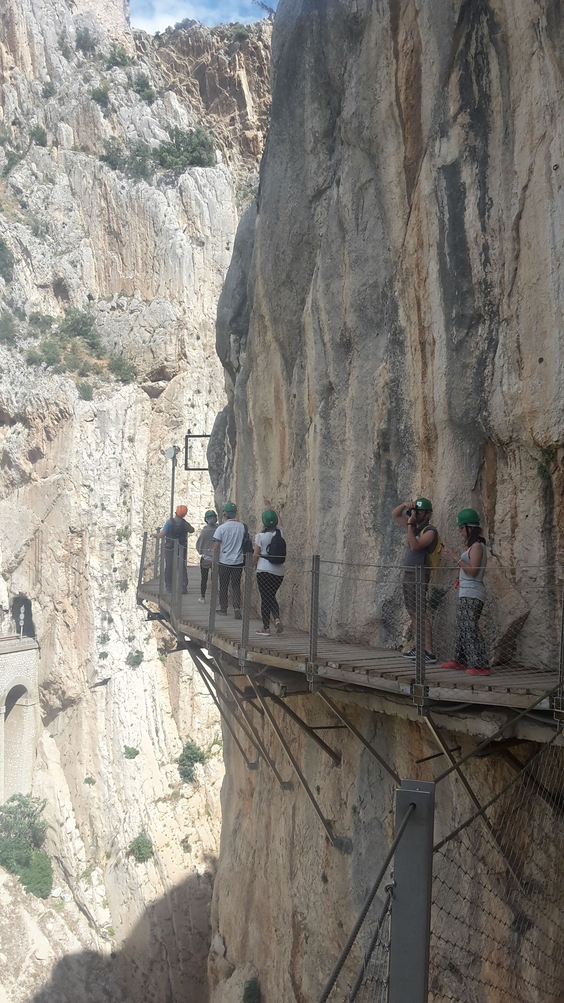 A group of people on a wooden platform overlooking a steep cliff.