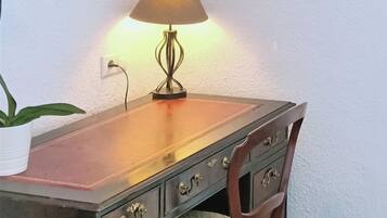 Ein Holztisch mit einer Lampe, einem Stuhl, einem Blumentopf und einem gerahmten Bild an der Wand.