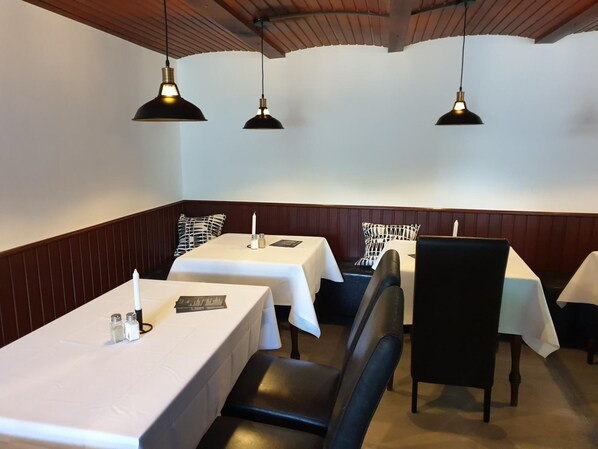 Un restaurante con cabinas y mesas, paneles de madera e iluminación colgante.