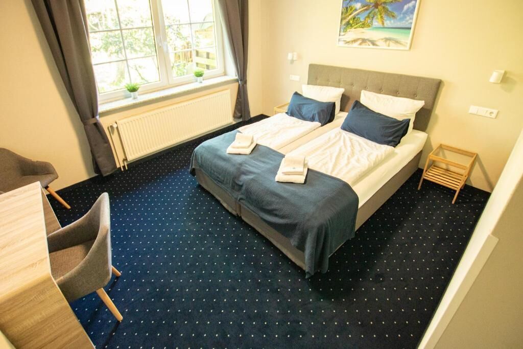 A hotel room with a bed, a desk, and a chair.