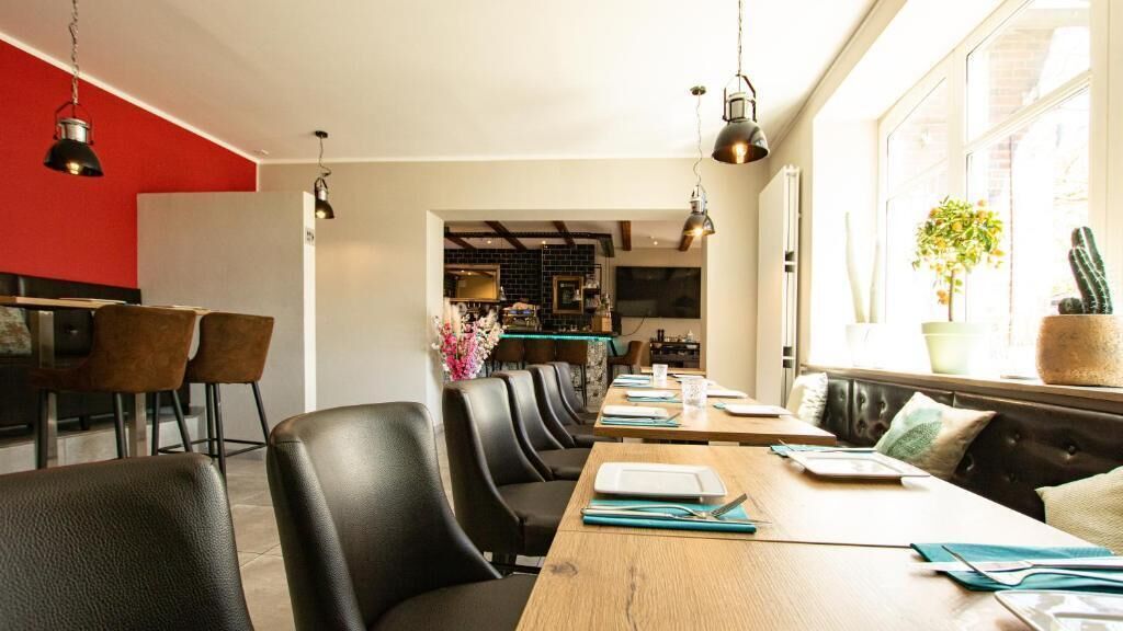 A dining area with a long wooden table, black chairs, and hanging pendant lights.
