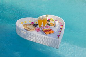 Un plateau flottant avec de la nourriture et des boissons, posé sur une piscine.