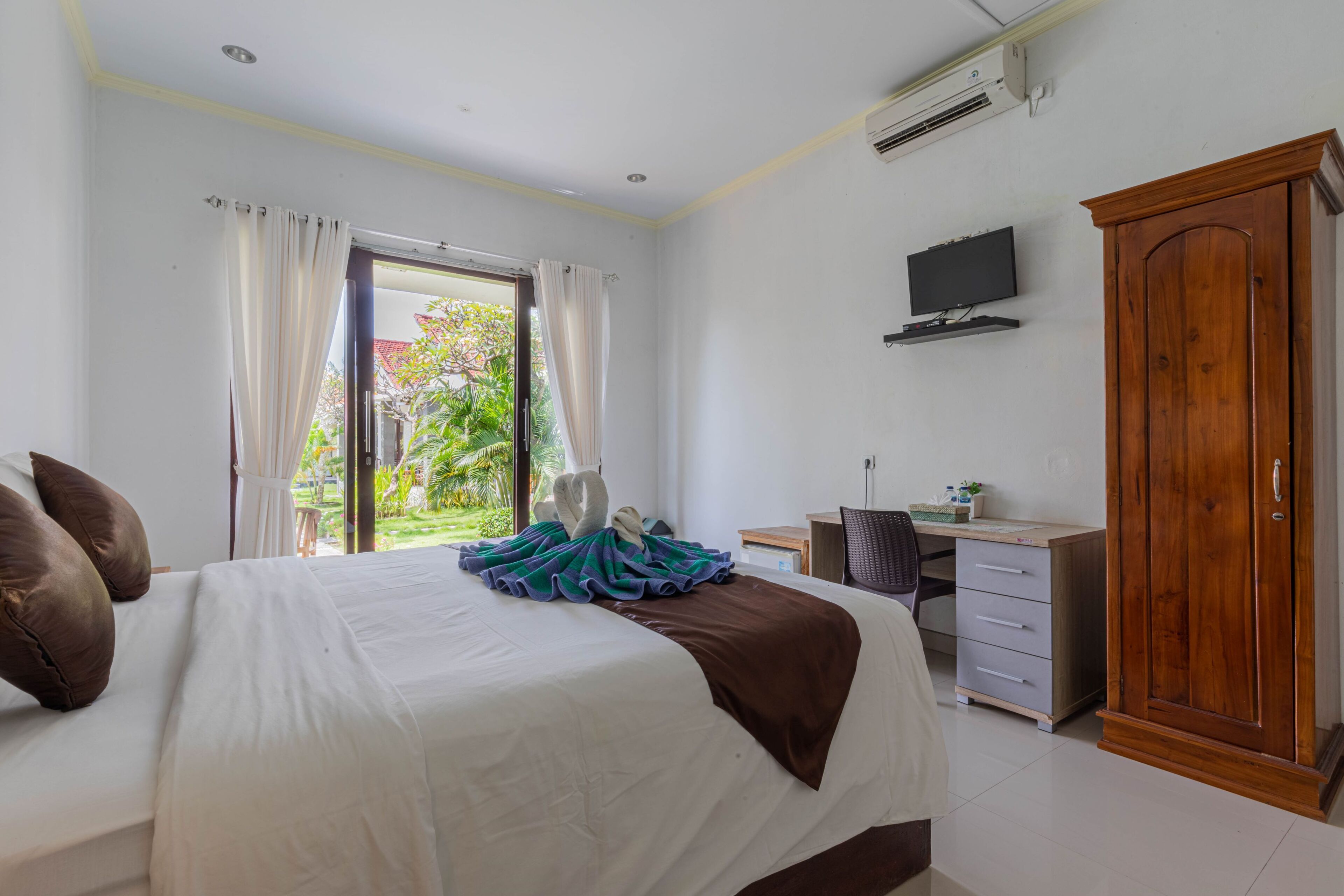 A hotel room with a bed, a desk, a wardrobe, and a television.