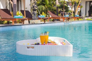 A poolside setting with lounge chairs and a floating tray with drinks and snacks. - Favorit Bungalows (Penida Island)