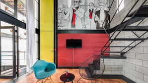 Een modern interieur met een rode bakstenen muur, een muurschildering, een trap en een blauwe stoel.