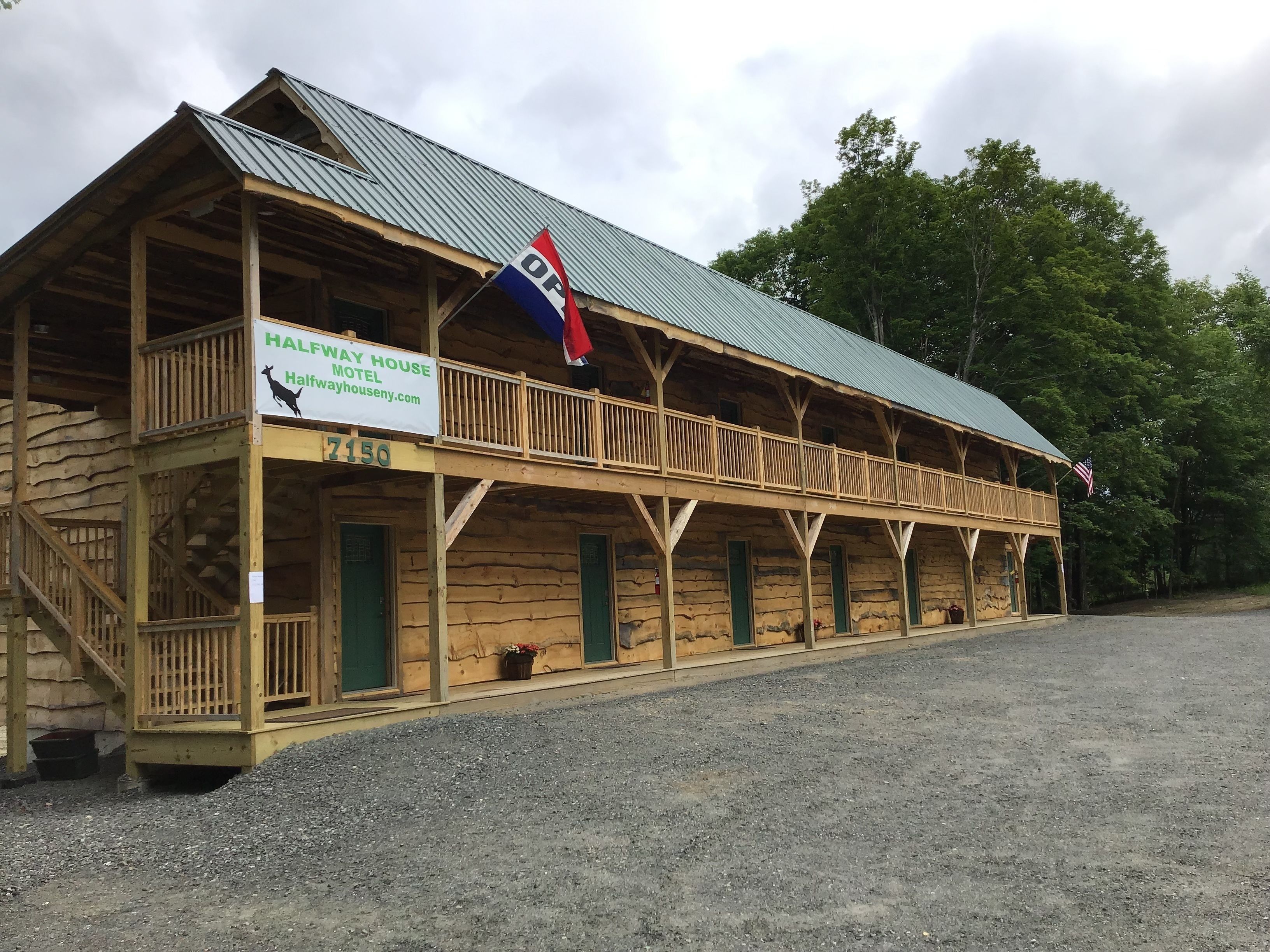 A wooden building with a balcony and a sign that reads "Halfway House Motel".