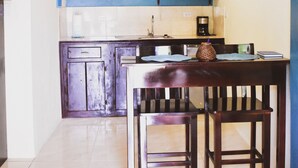 Een keuken met een blauwe accentmuur, een magnetron, een koffiezetapparaat en een klok.