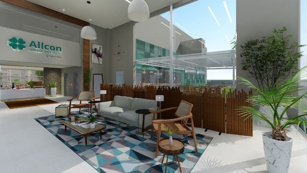 En moderne hotellobby med reception, siddeområde og store vinduer med udsigt over interiøret.