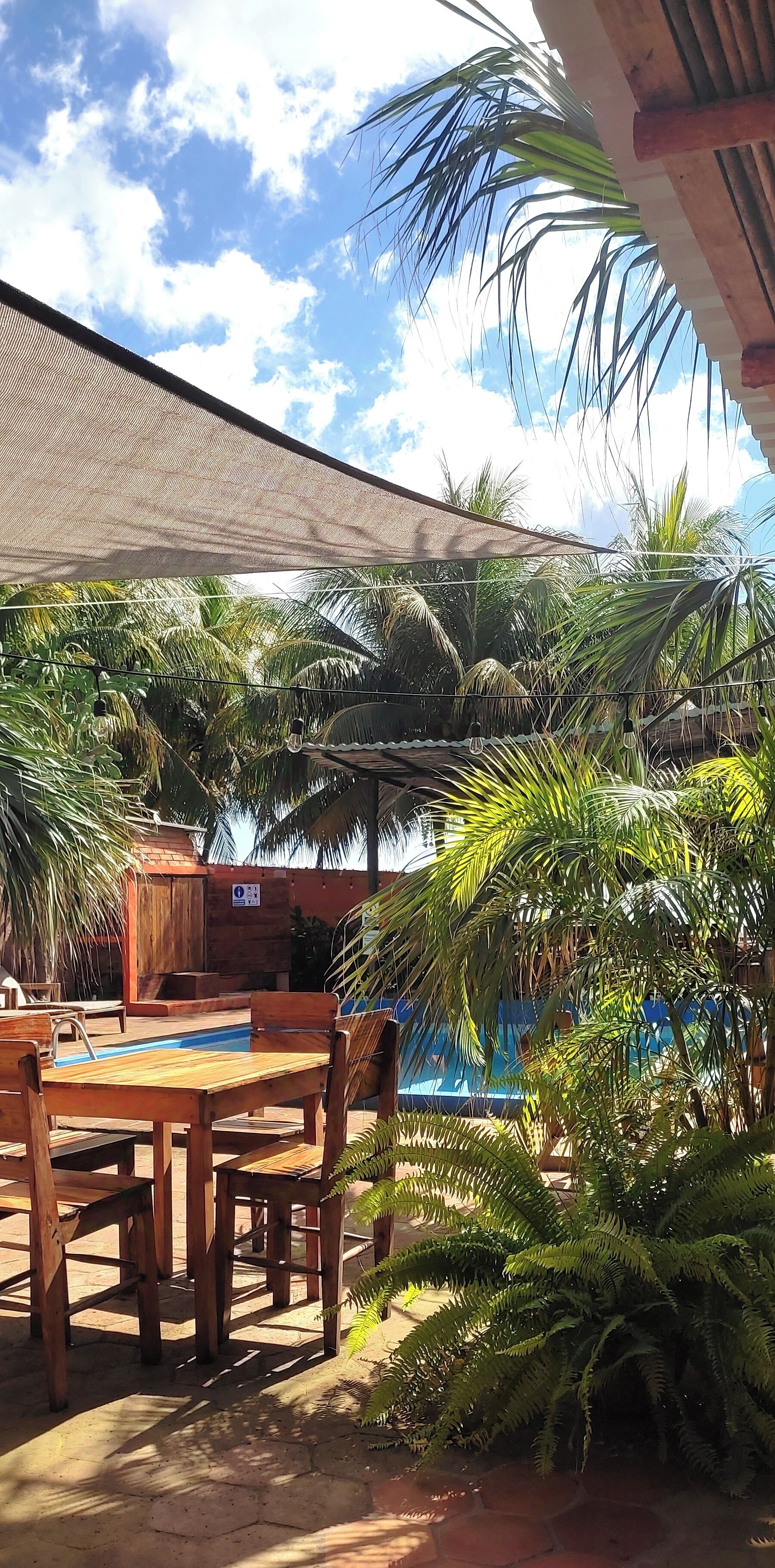 Uma área à beira da piscina com mobiliário de madeira e um guarda-sol.