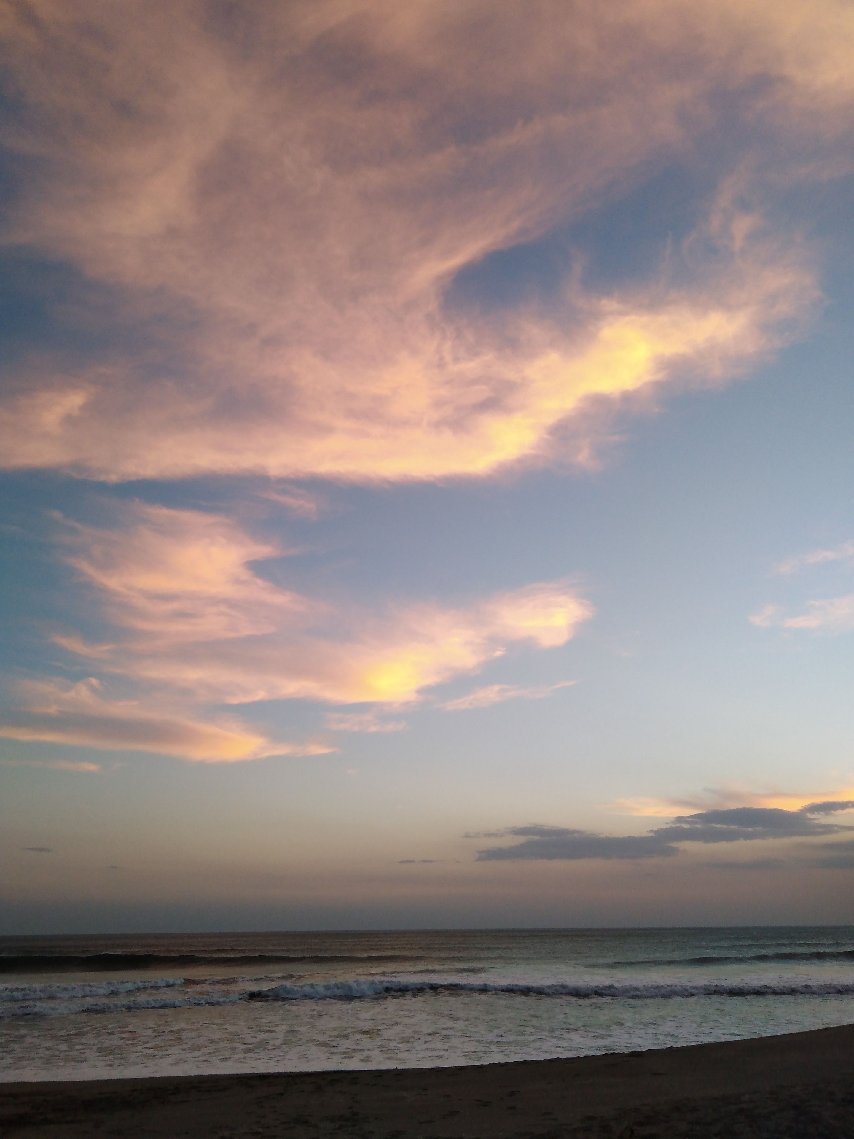 A beach with a clear sky and clouds.