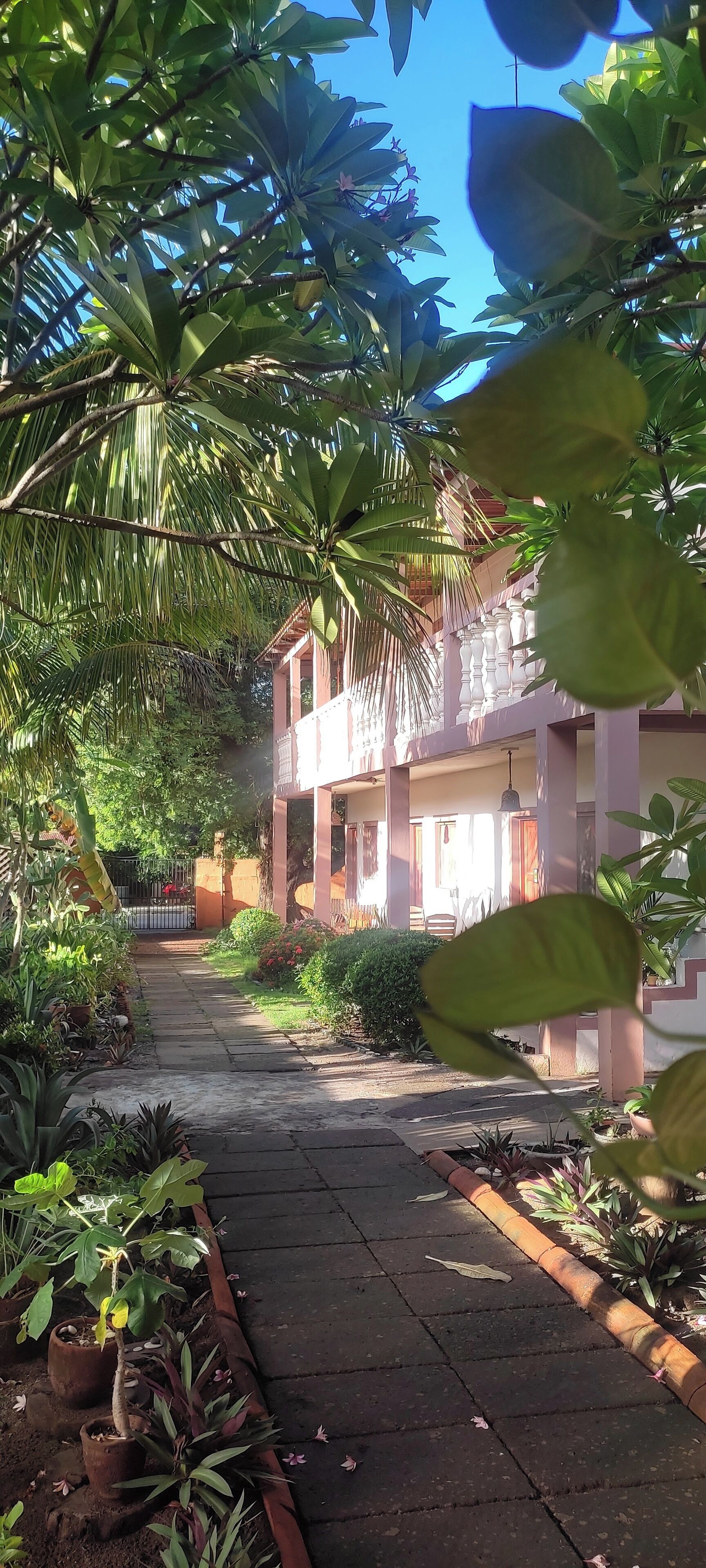 A pathway leading to a building with a balcony and a gated entrance.