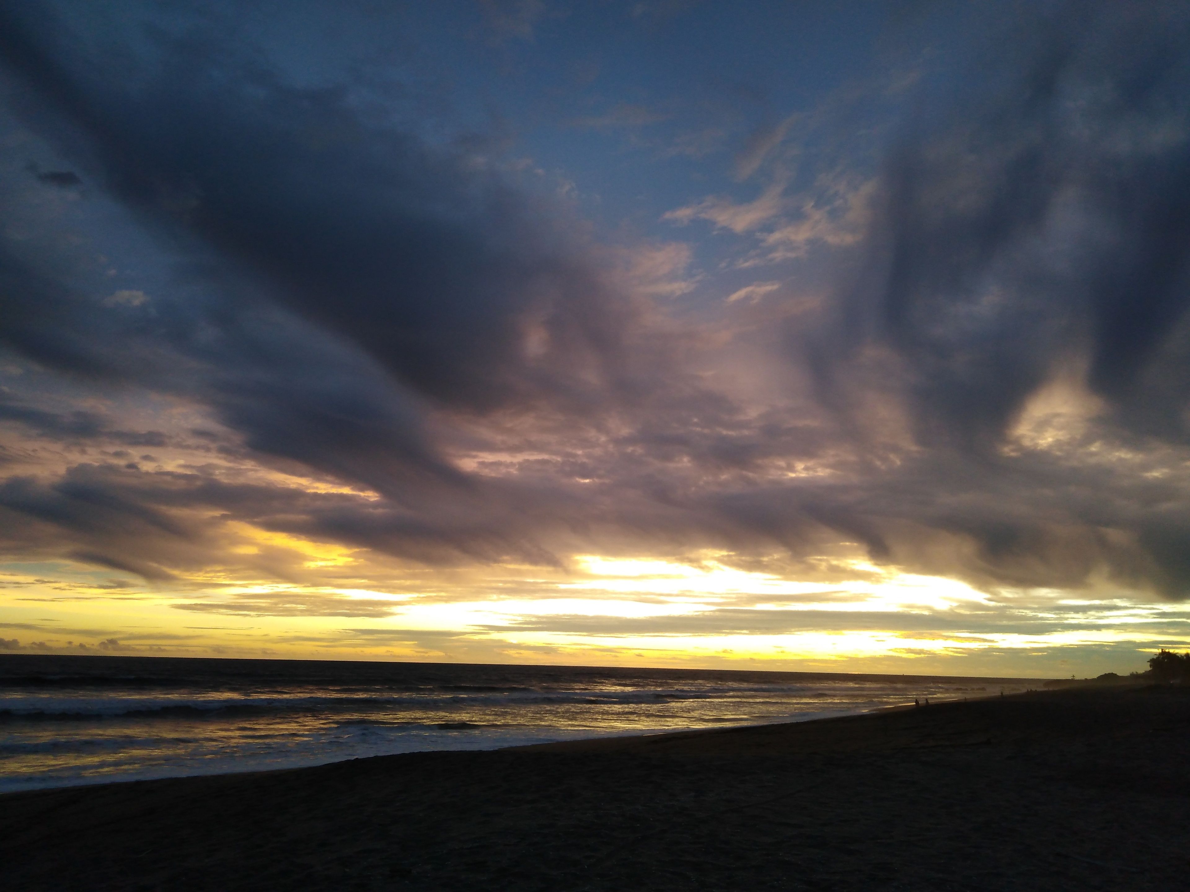 Una spiaggia con un tramonto e nuvole.
