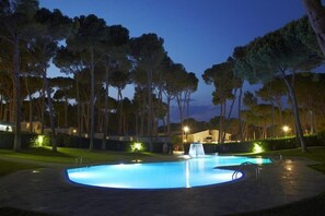 A swimming pool at dusk with surrounding trees and a building in the background. - Camping Interpals (Pals)