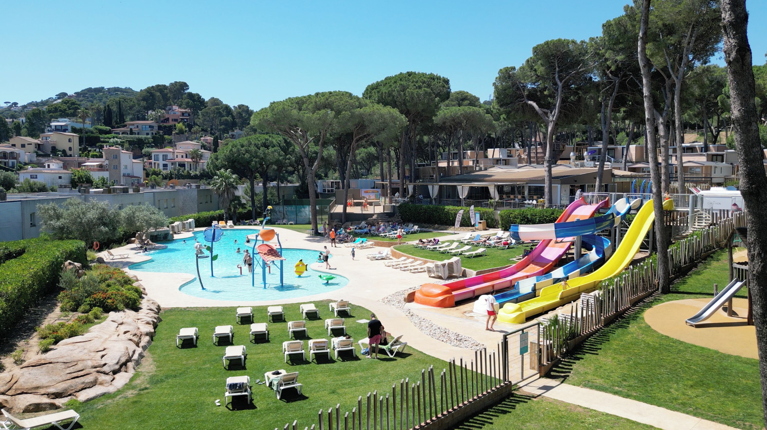 Un complex turístic amb piscina, tobogans aquàtics i gandules.