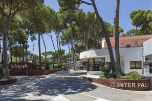A building with a curved facade, a sign reading "INTERPALS," and a parking area with trees and a clear sky. - Camping Interpals (Pals)