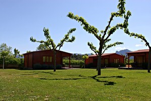 Un edificio de fachada roja, rodeado de un área verde con árboles.