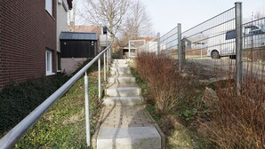 Een bakstenen gebouw met een metalen hek en een geplaveid pad dat naar een poort leidt.