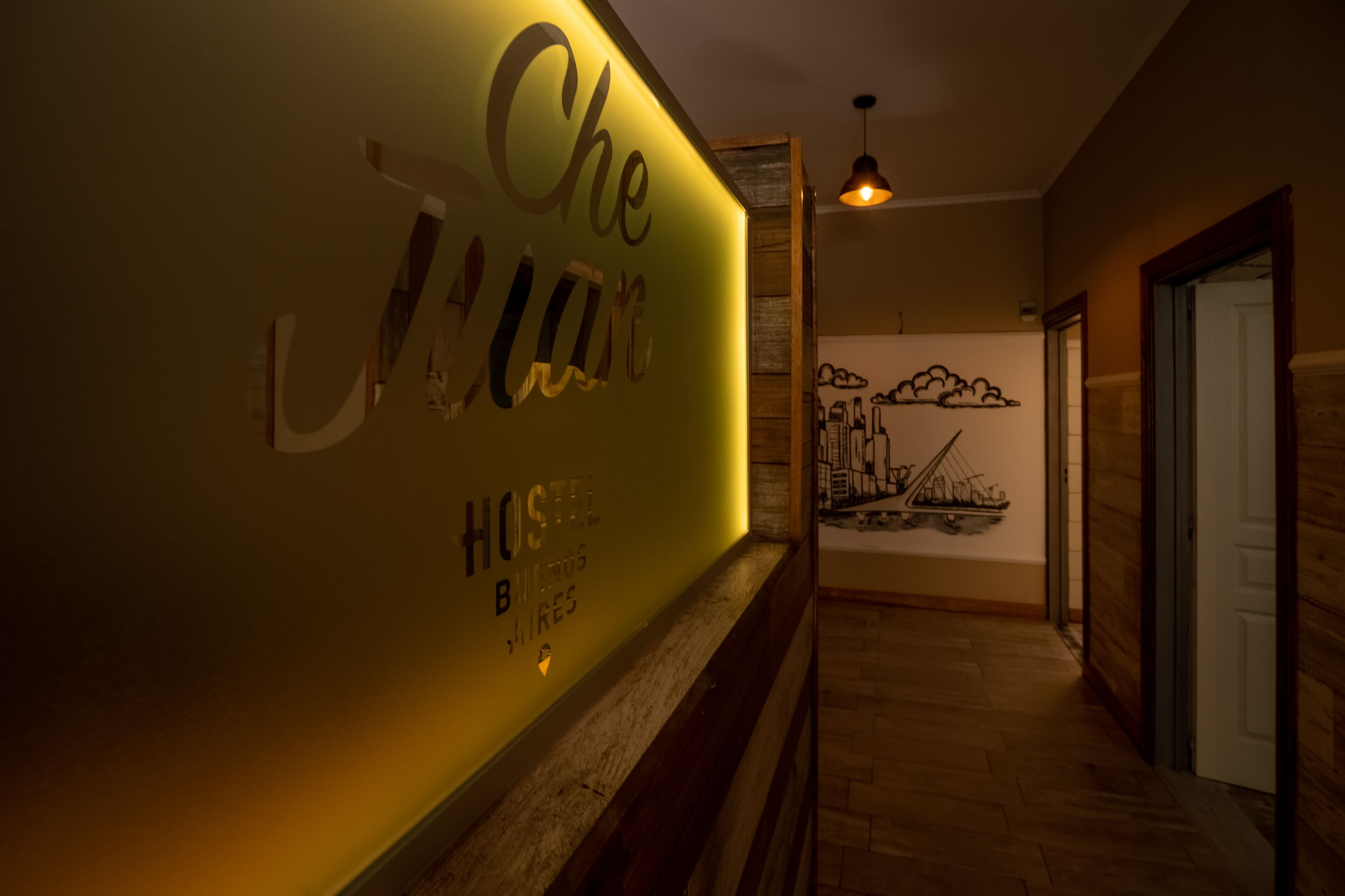 A hallway with a wall displaying the text "Che J'AIme HOSTEL B" and a mural of a cityscape.