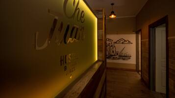Un couloir dont un mur est décoré avec l’inscription « Che J’aime Hostel B » et une fresque représentant un paysage urbain.