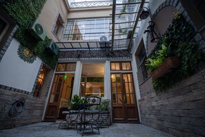 Un patio con una mesa y sillas de madera, rodeado de muros de piedra y plantas en macetas.