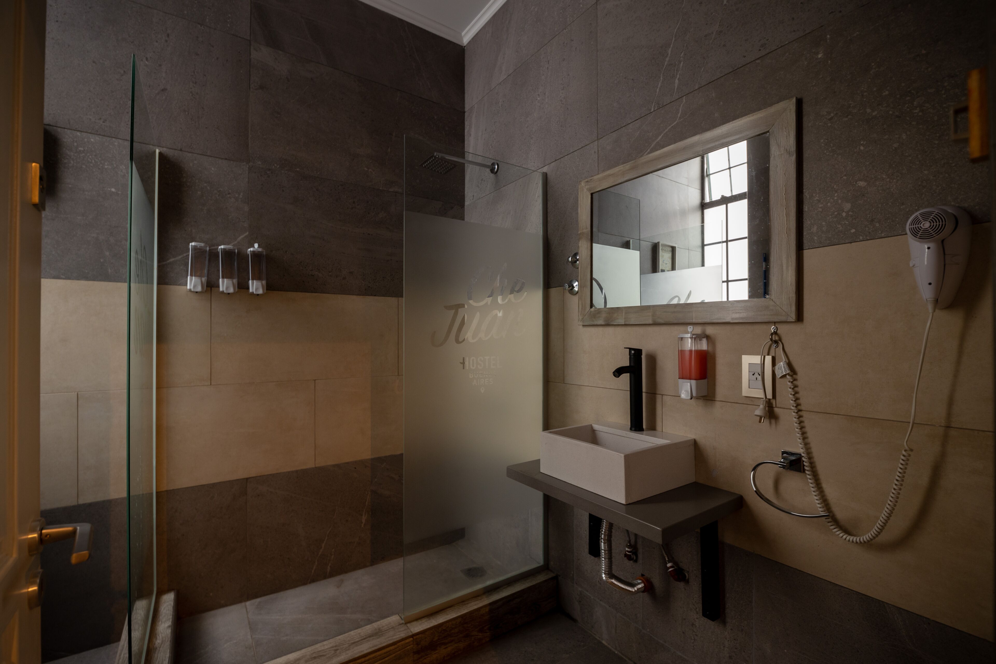 A modern bathroom with a glass shower enclosure, a large mirror, and a built-in sink.