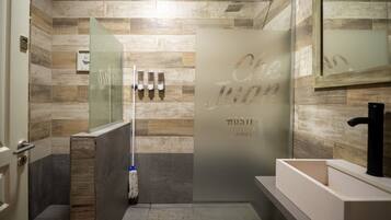 A modern bathroom with a glass shower enclosure, a wooden wall backsplash, and a large mirror above the sink.