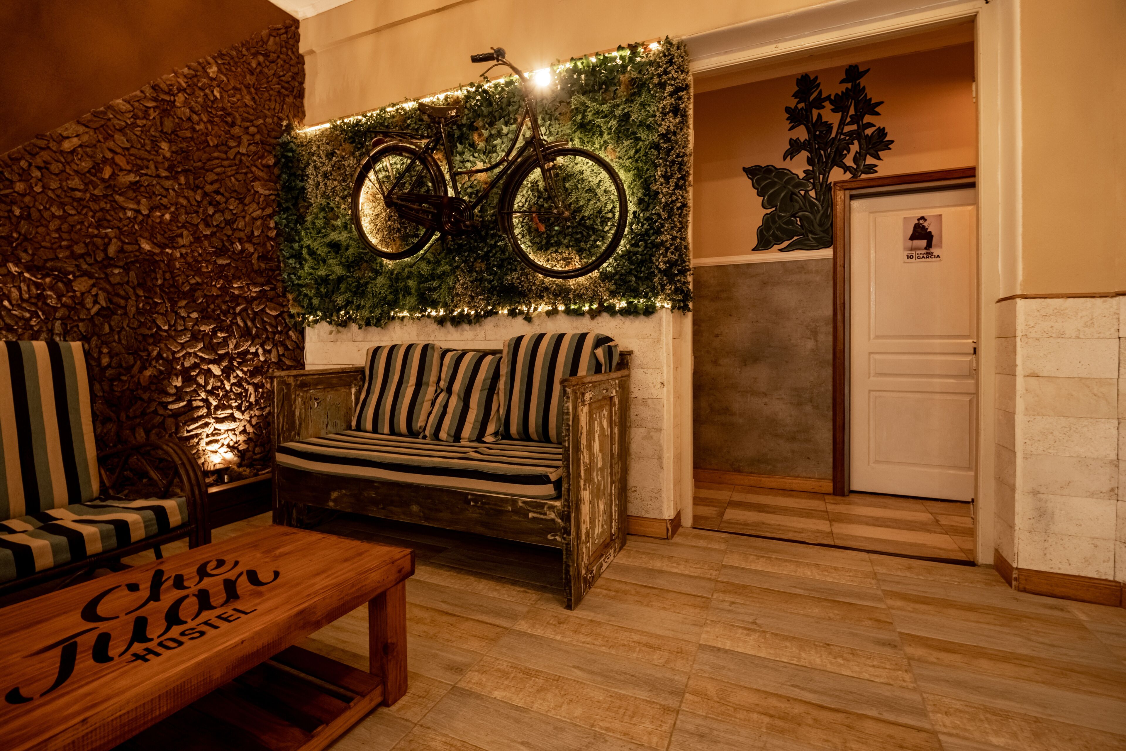 Une pièce chaleureuse avec un banc en bois, un canapé orné de coussins à rayures et une bicyclette décorative accrochée au mur.