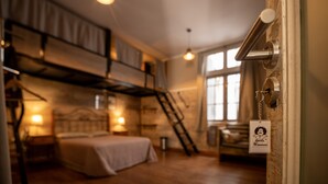 A room with a bunk bed, a ladder, a desk, and a hanging light fixture. - Che Juan Hostel BA (Buenos Aires)