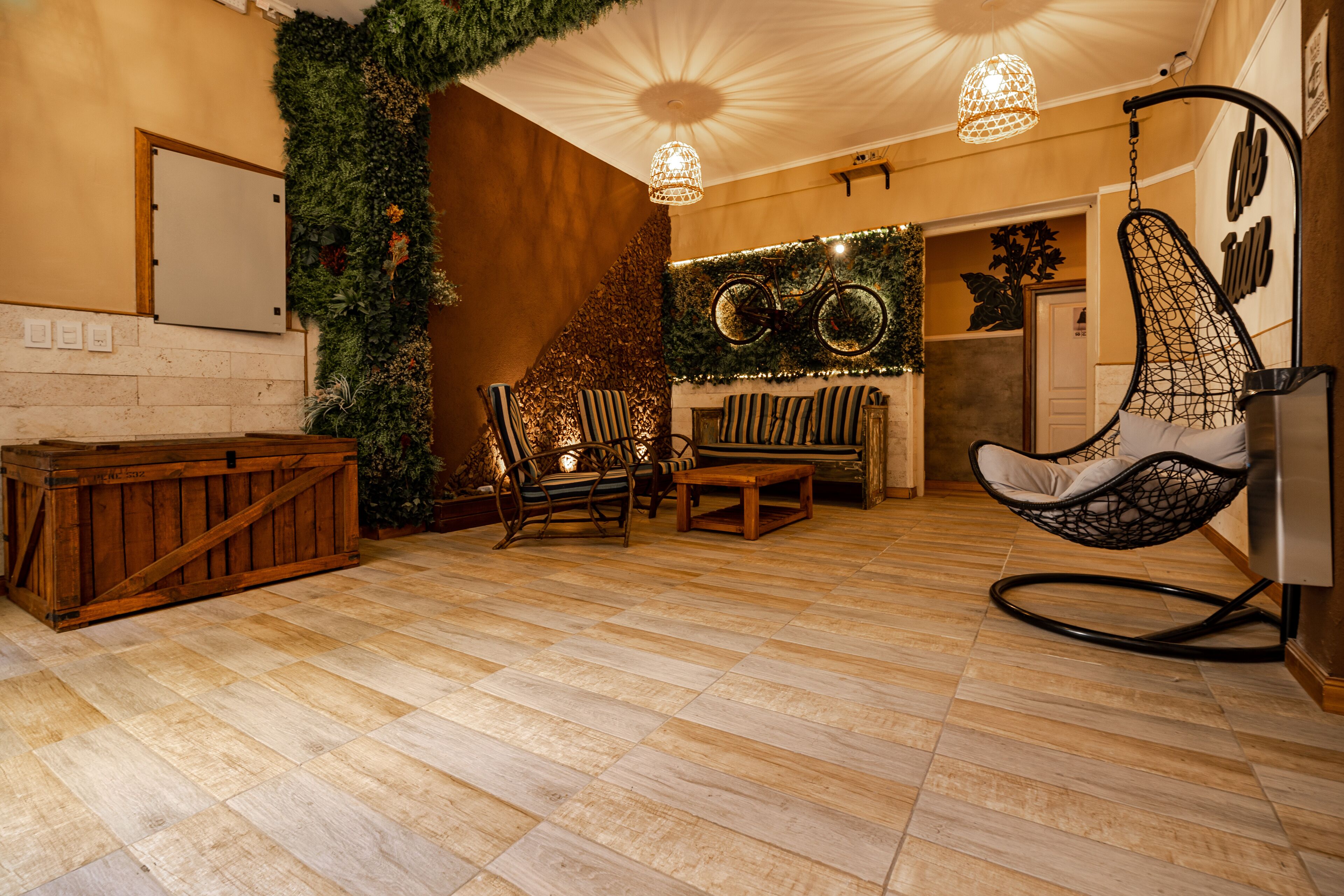 A cozy room with a wooden floor, a hanging chair, a bench, and a wall-mounted bicycle.
