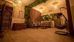 A room with a wooden floor, a wooden bench, a hanging chair, and a wall with a circular design. - Che Juan Hostel BA (Buenos Aires)