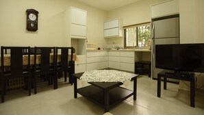 A compact living space with a dining area, a kitchen, a television, and a clock on the wall. - The Garden Apartment (Nazareth)