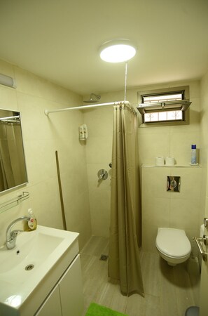 A bathroom with a sink, toilet, shower, and a mirror.