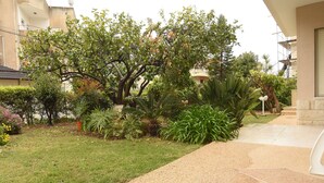A landscaped garden with various plants and a paved walkway. - The Garden Apartment (Nazareth)