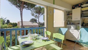 A balcony with a table set for two, chairs, a microwave, and a cabinet. - le Clos des Lavandes by Interhome (Bandol)