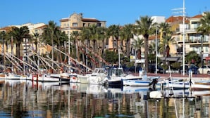 A marina with boats docked, palm trees, and buildings in the background. - le Clos des Lavandes by Interhome (Bandol)