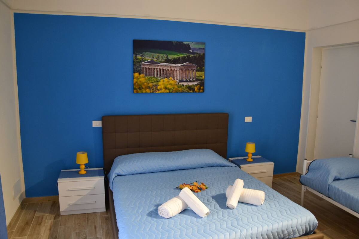 Una habitación de hotel con una cama grande, dos mesitas de noche y un cuadro en la pared.
