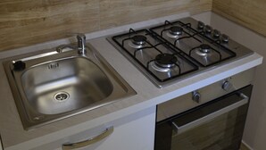 A kitchen with a stainless steel sink, a gas stove, and a built-in oven. - B&B Stella Maris Trapani Centro (Trapani)
