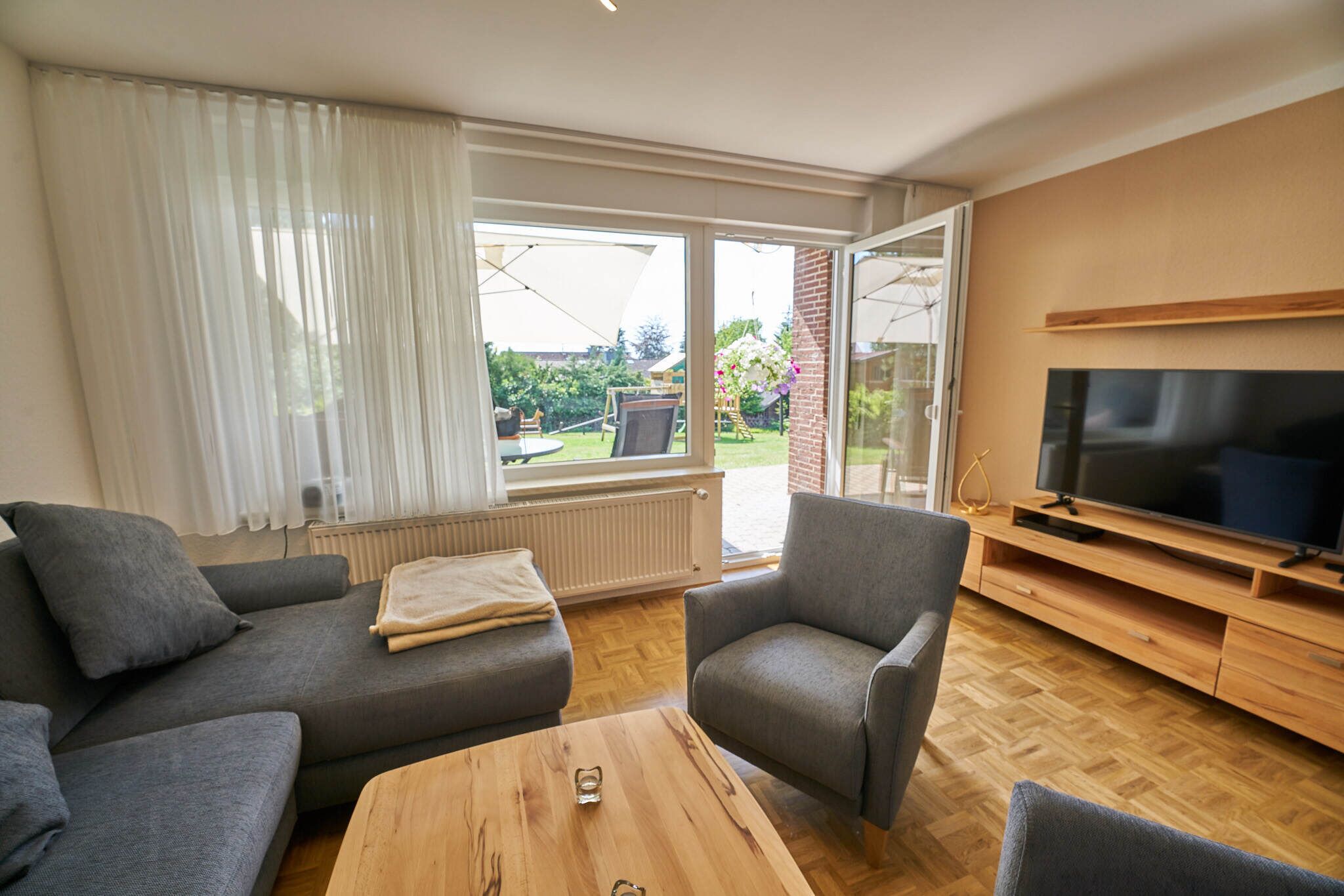 A modern living room with a sofa, armchairs, a coffee table, and a TV.