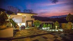 A modern house with a checkered driveway, a covered patio, and a view of the mountains at dusk. - La Toscana Hills (Atenas)